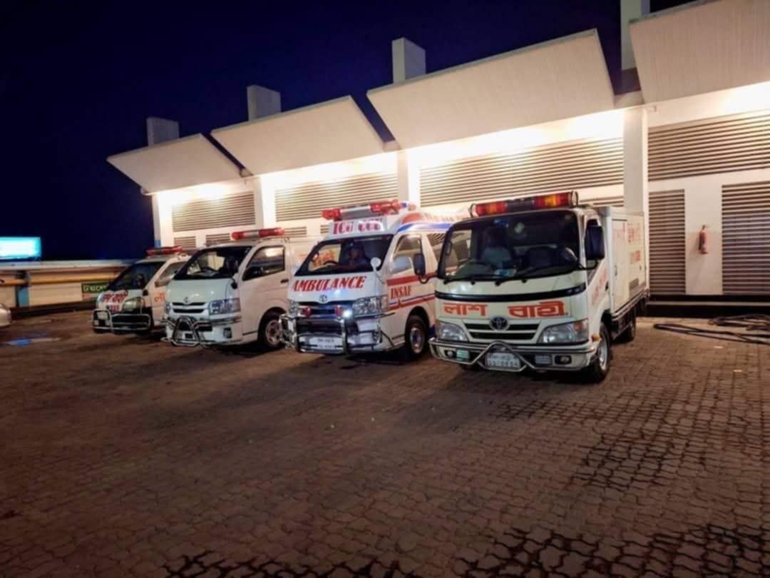Ambulances and a freezer van lined up at night in Dhaka